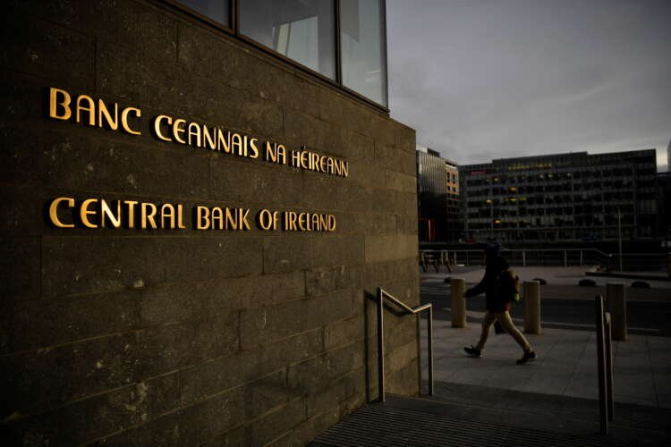 Man walks past the Central Bank of Ireland in Dublin, reflecting banking sector changes - Global Banking & Finance Review