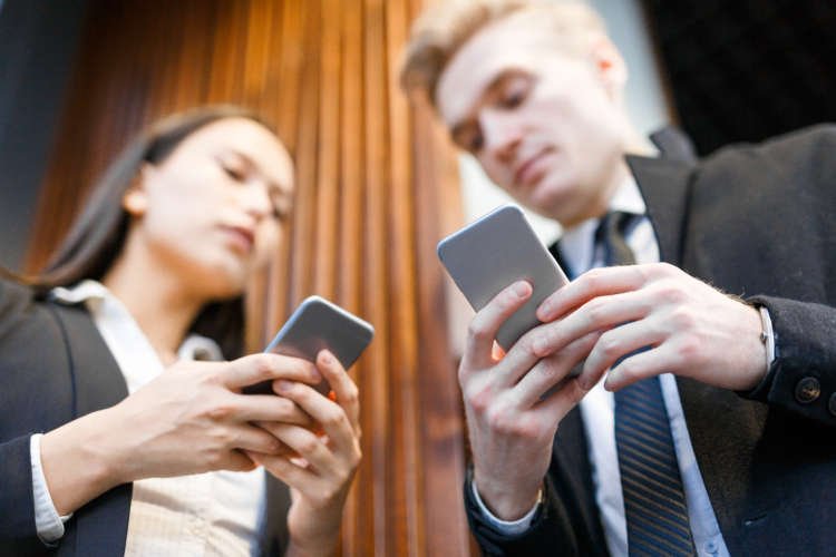 Two individuals communicating via smartphones, showcasing DTC business transformation through direct messaging - Global Banking & Finance Review