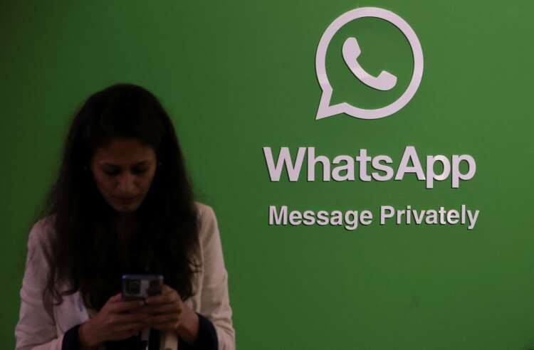 A woman uses her smartphone next to the WhatsApp logo during a technology conference - Global Banking & Finance Review