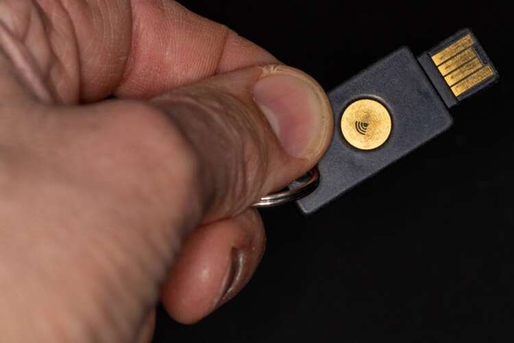 Hand holding a FIDO2 security key illustrating passwordless authentication - Global Banking & Finance Review