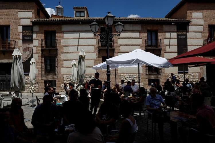 A waiter serves customers at a busy restaurant terrace in Madrid, reflecting Spain's service sector amid economic concerns - Global Banking & Finance Review