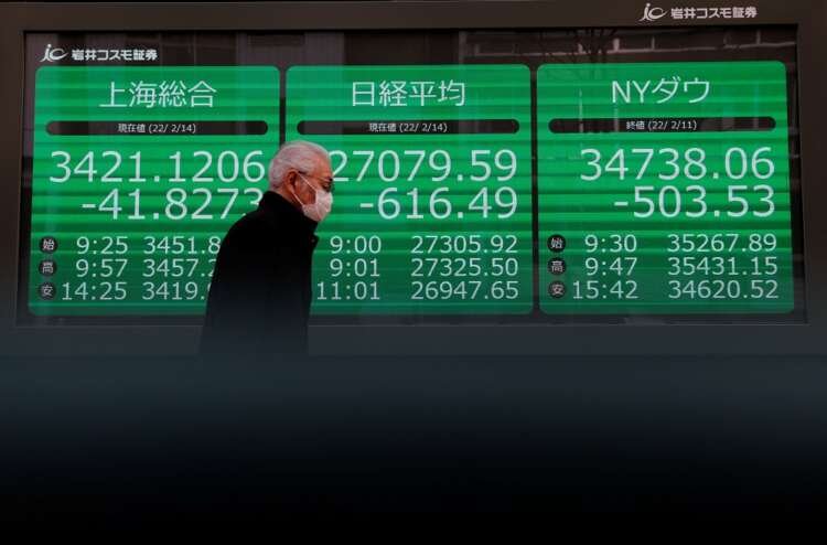 A man in a protective face mask walks by a Tokyo brokerage amid stock market tensions - Global Banking & Finance Review