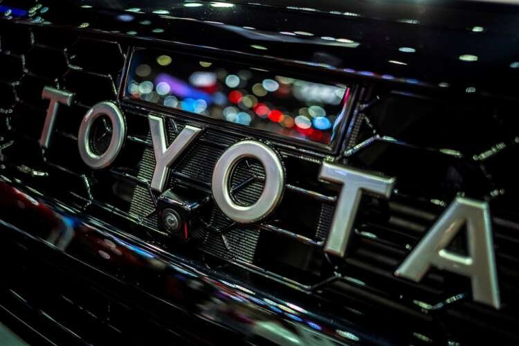 Toyota logo displayed at an auto show reflecting challenges in production - Global Banking & Finance Review