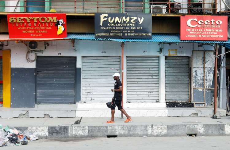 A man walks past shops remaining closed in Lagos