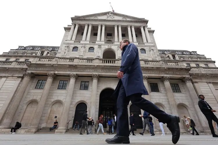 Bank of England building with financial charts showing rate cuts and inflation trends - Global Banking & Finance Review