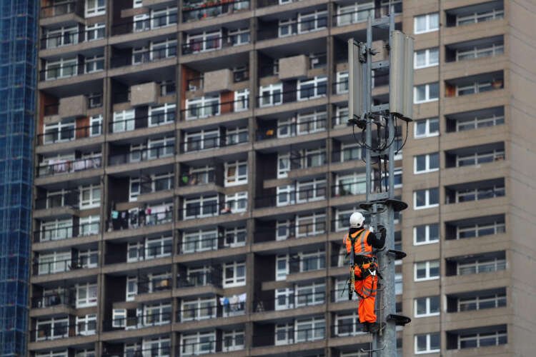 An engineer works on a 5G mobile mast in London, showcasing Britain's telecom advancements - Global Banking & Finance Review