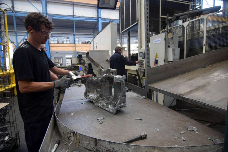 A worker at Evtec Aluminium Ltd sands metal, showcasing low-carbon aluminium production - Global Banking & Finance Review