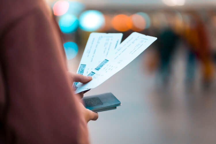 A woman excitedly holds event tickets and boarding passes, symbolizing travel and entertainment access - Global Banking & Finance Review