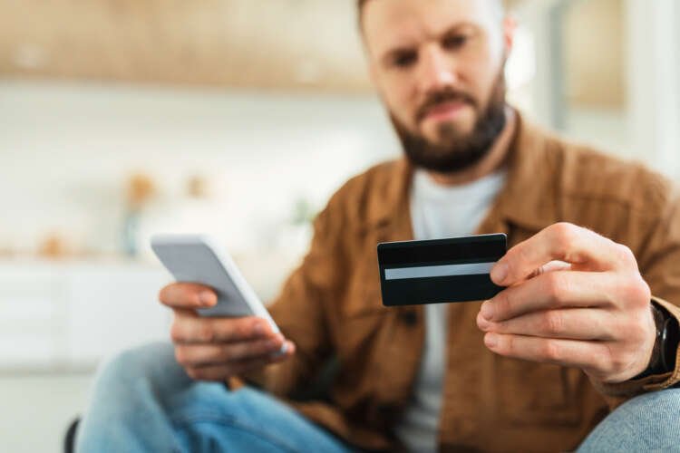 Man making an online payment with a credit card and phone, symbolizing fintech solutions - Global Banking & Finance Review