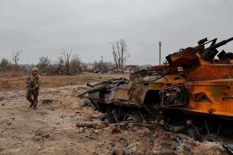 Ukrainian service member inspects destroyed Russian military vehicle amidst conflict - Global Banking & Finance Review