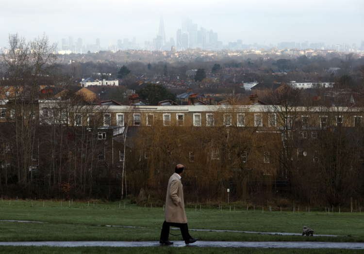 A man walking through a park in London, overlooking the financial district, highlighting the surge in guarantor loan complaints - Global Banking & Finance Review