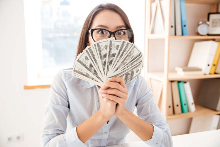 Businesswoman holding money in hand near face