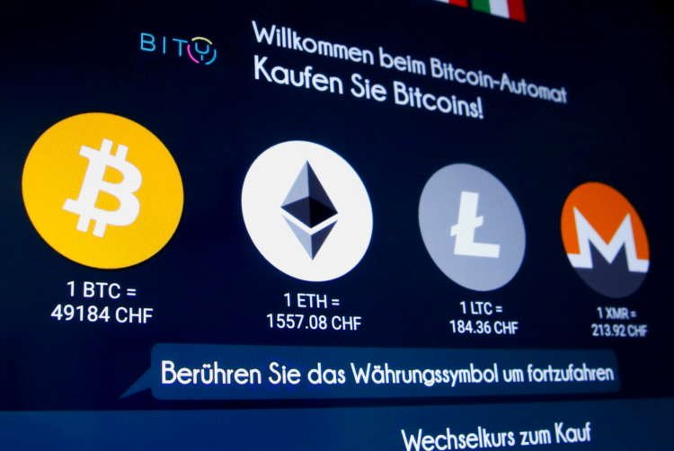 FILE PHOTO: The exchange rates and logos of Bitcoin, Ether, Litecoin and Monero are seen on the display of a cryptocurrency ATM in Zurich