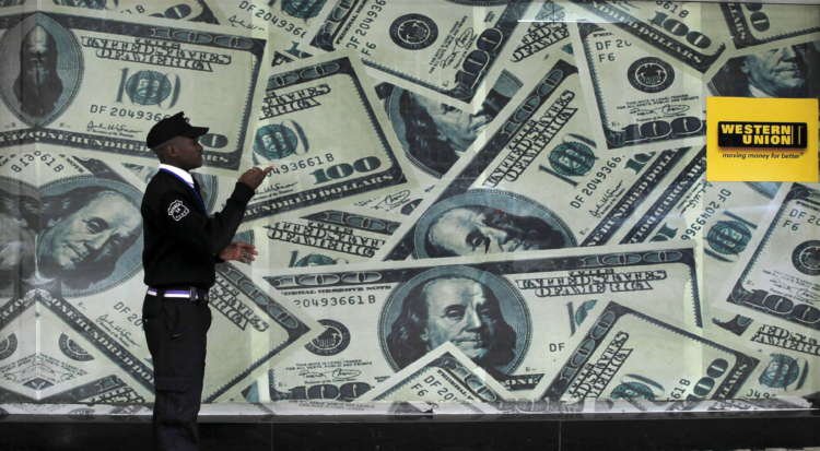 FILE PHOTO: A security guard walks past a montage of old U.S. dollar bills outside a currency exchange bureau ahead of a scheduled State visit by the U.S. President Barack Obama in Kenya’s capital Nairobi