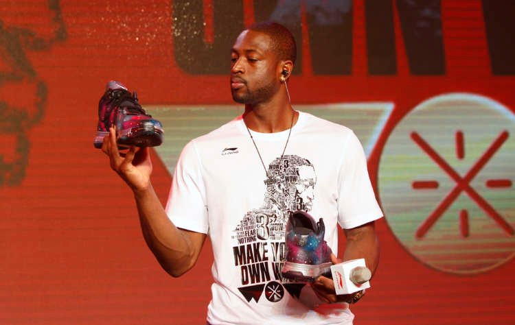 NBA Miami Heat’s Wade looks at a pair of Li Ning’s Way of Wade sneakers designed by a fan during a promotional event for the company in Beijing