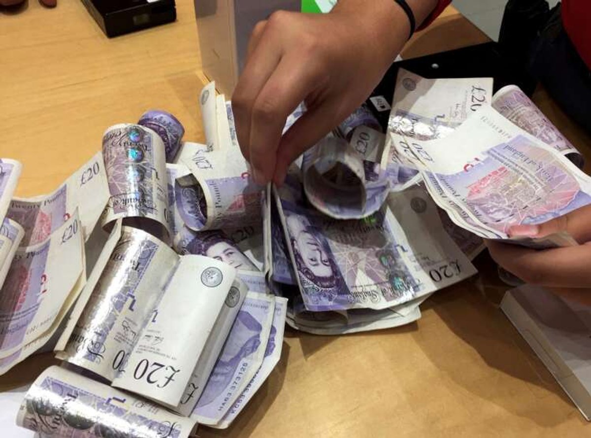 Shop assistant counting British Pound Sterling notes amidst currency market fluctuations - Global Banking & Finance Review