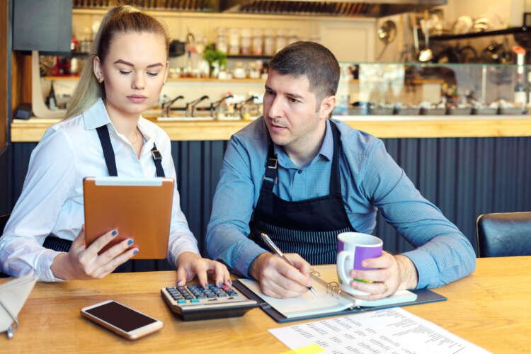 Small business owners reviewing financial documents in a coffee shop - Capital access challenges - Global Banking & Finance Review