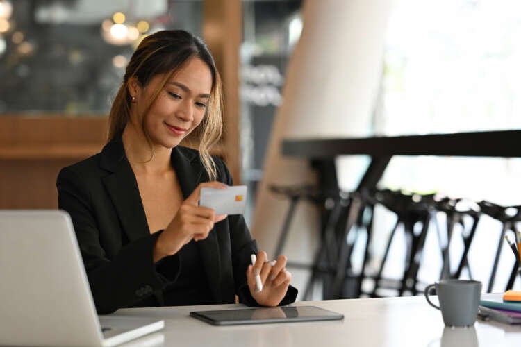 Portrait of an Asian businesswoman using a tablet and laptop, symbolizing IoT's impact on banking - Global Banking & Finance Review