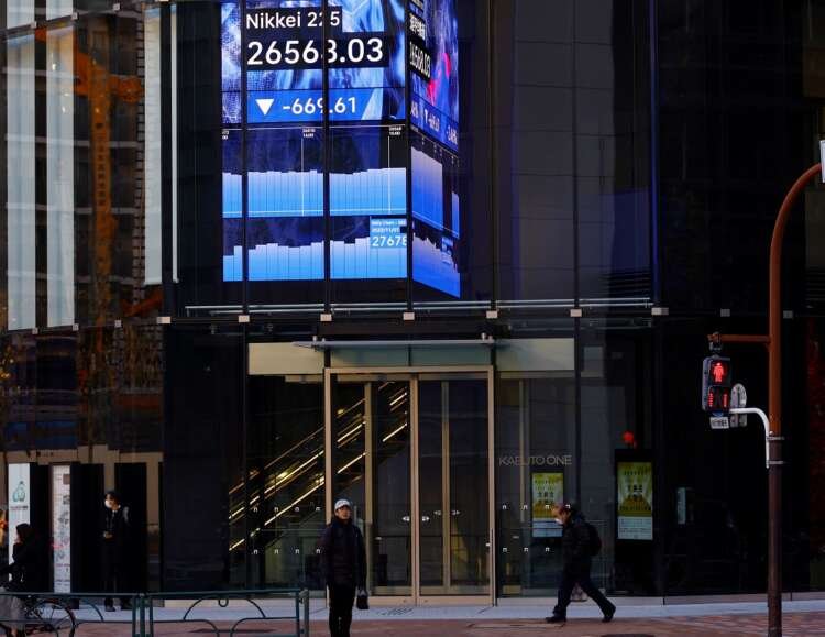 People walking past an electric board displaying the Nikkei index in Tokyo - Global Banking & Finance Review