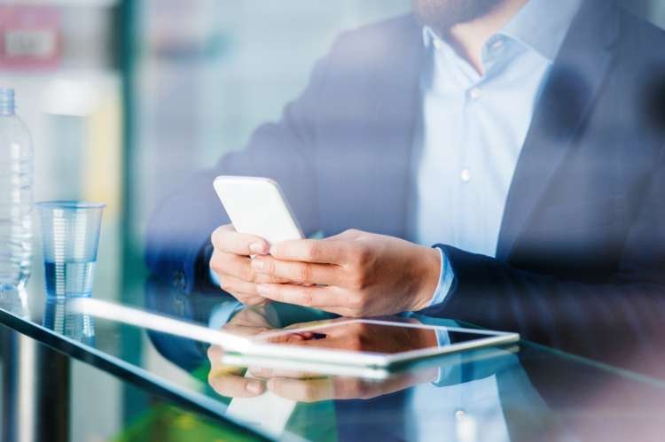 Young man using smartphone, symbolizing growth and transparency in finance - Global Banking & Finance Review