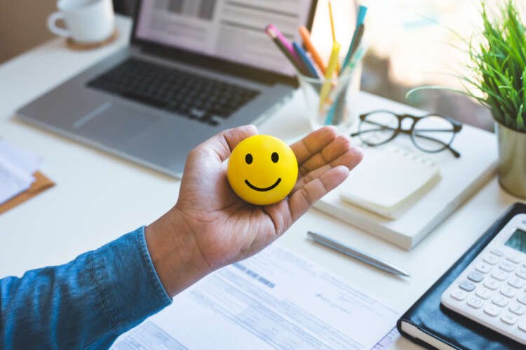 A thoughtful male hand holding a mindfulness emoticon, symbolizing mental health in the workplace - Global Banking & Finance Review