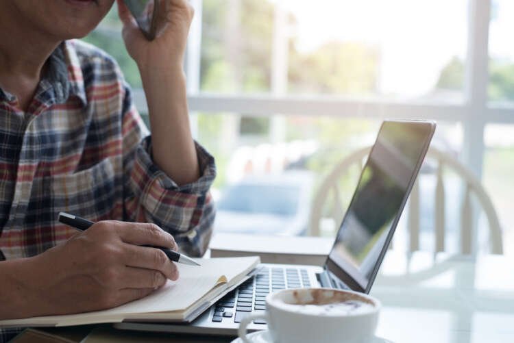 Man working remotely on a laptop in a cafe, exploring salary implications - Global Banking & Finance Review