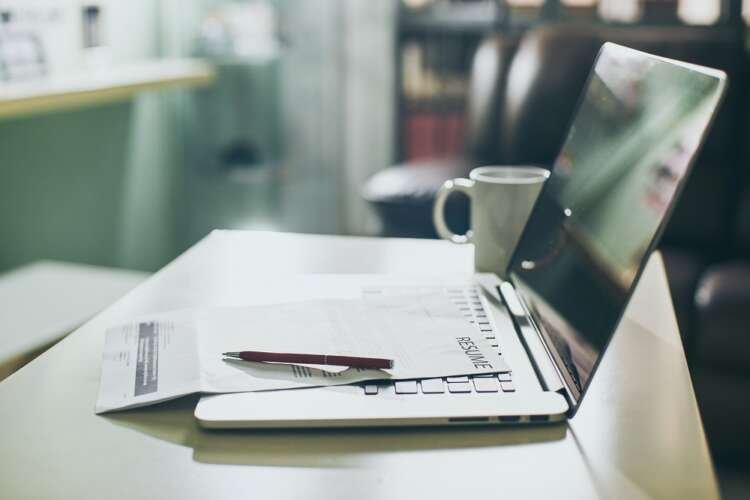 Modern workspace with laptop, tablet, and resume for job search - Global Banking & Finance Review