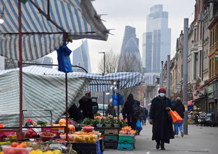 People shopping at market stalls in London with the City of London skyline - Global Banking & Finance Review