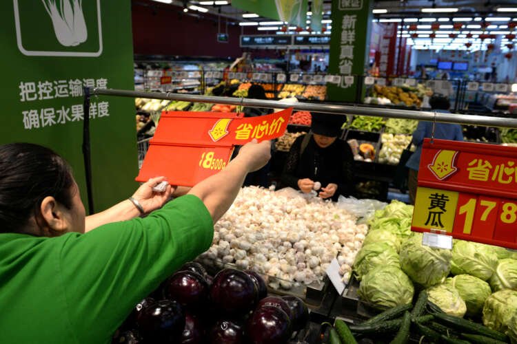 Price tag insertion by a staff member at Walmart in Beijing, reflecting China's disinflation - Global Banking & Finance Review