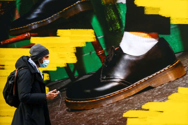 FILE PHOTO: A woman walks past the window of a “Dr Martens” shoe shop amid the coronavirus disease (COVID-19) outbreak in central Madrid
