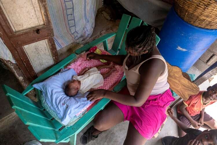 Haitian earthquake survivor cradles newborn amidst damaged home - Global Banking & Finance Review
