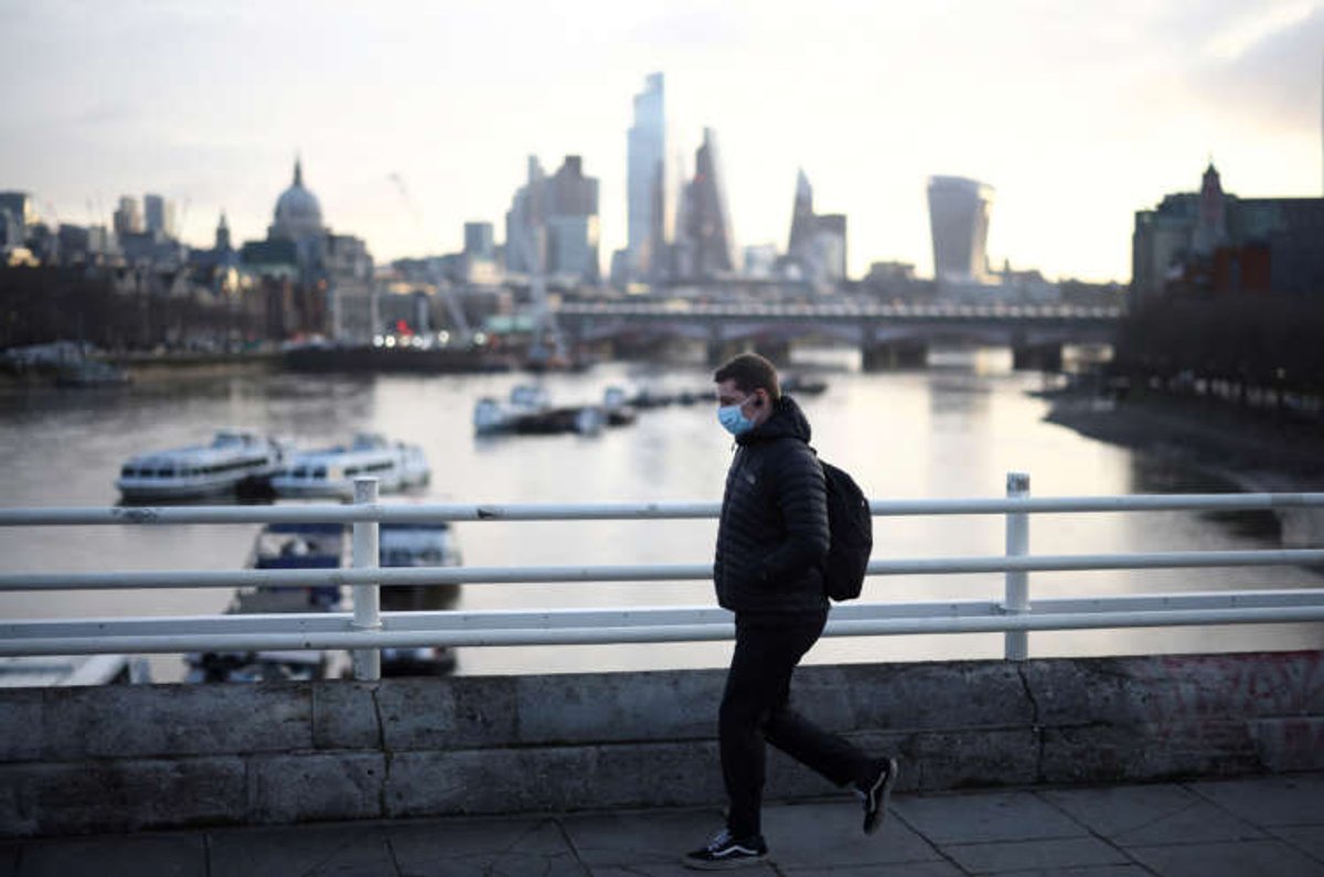 A man in a mask walks across Waterloo Bridge during the COVID-19 pandemic - Global Banking & Finance Review