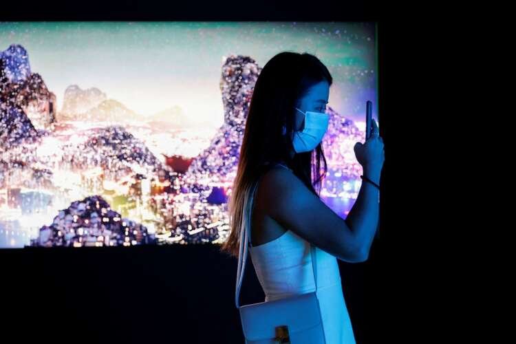 FILE PHOTO: Visitor takes a photo in front of a video installation which will be converted into NFTs and auctioned online at Sotheby’s, in Hong Kong