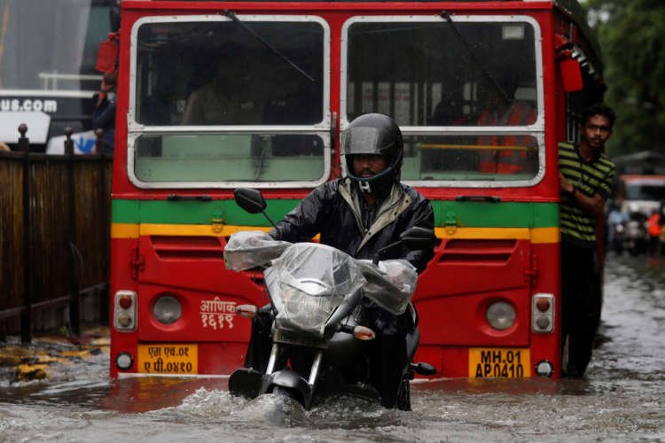 A man navigating a flooded street in Mumbai during chaotic monsoon rains - Global Banking & Finance Review