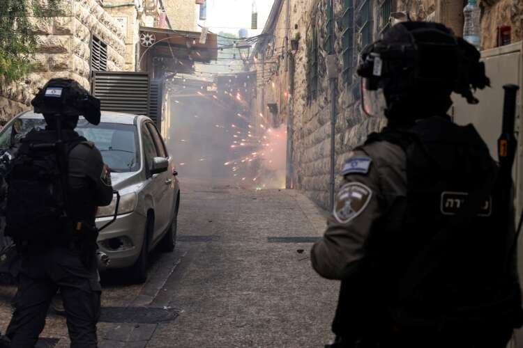 Israeli border police force stand by as Palestinian protestors shoot fireworks towards them in an alley in Jerusalem’s Old City