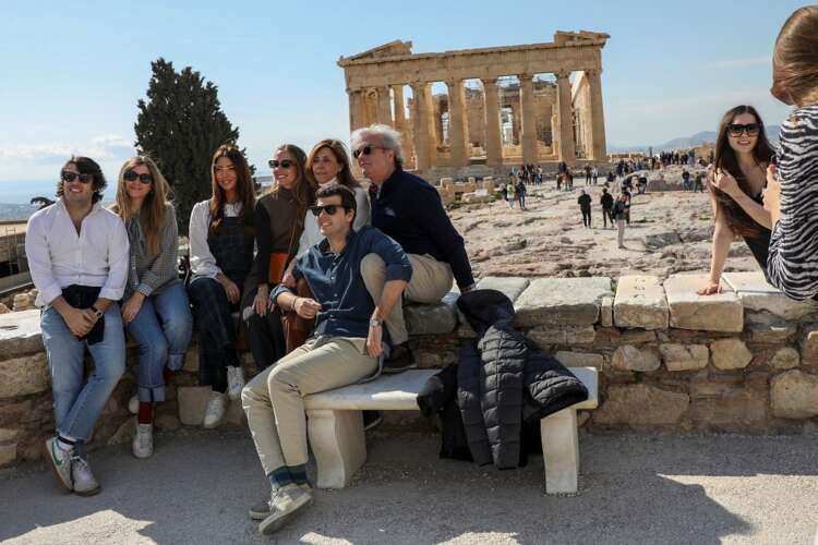 FILE PHOTO: Visitors pose for a photo with the ancient Parthenon Temple seen in the background, atop the Acropolis hill archaeological site in Athens