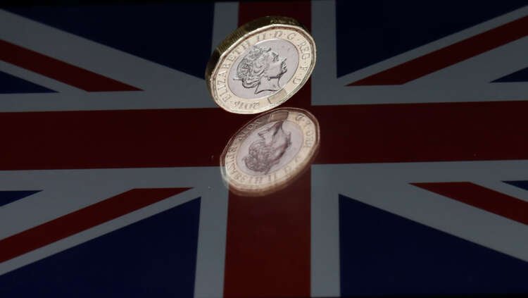 One pound coin resting on a Union Flag, symbolizing UK government savings initiative - Global Banking & Finance Review