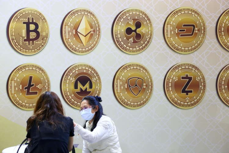FILE PHOTO: Customers talk against a backboard with signs of cryptocurrency during 2020 Taipei International Finance Expo in Taipei,
