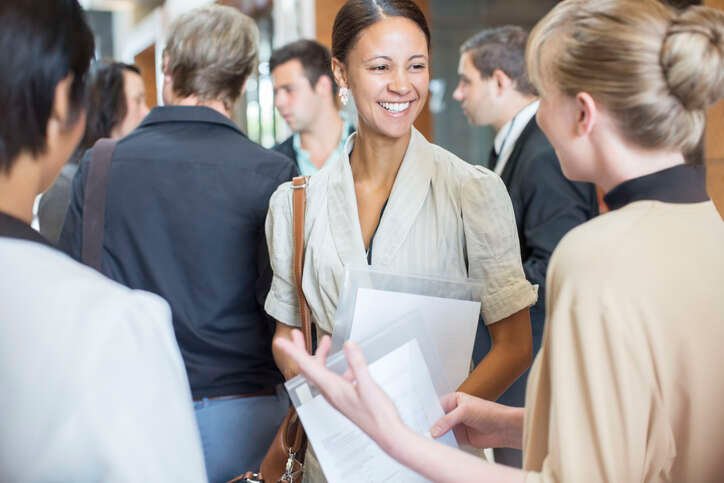 Two women engaging in conversation with files, symbolizing networking in business - Global Banking & Finance Review
