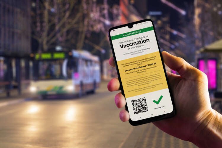 Smartphone showing COVID-19 vaccination certificate in hand, highlighting KYC challenges - Global Banking & Finance Review