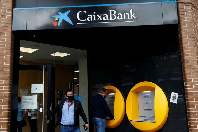 A person exits a Caixabank branch in Madrid amidst news of job cuts - Global Banking & Finance Review