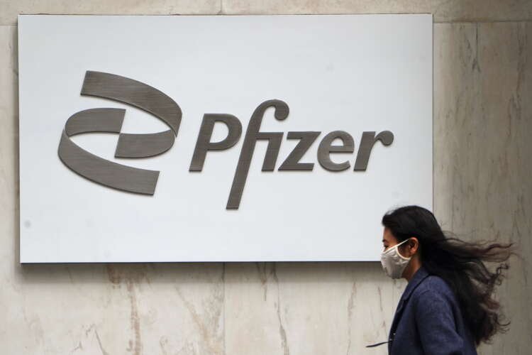Person walking past Pfizer logo, highlighting COVID vaccine effectiveness against Delta variant - Global Banking & Finance Review