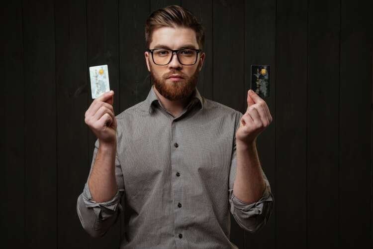 Serious bearded man in glasses holds metal credit cards, symbolizing the future of banking - Global Banking & Finance Review