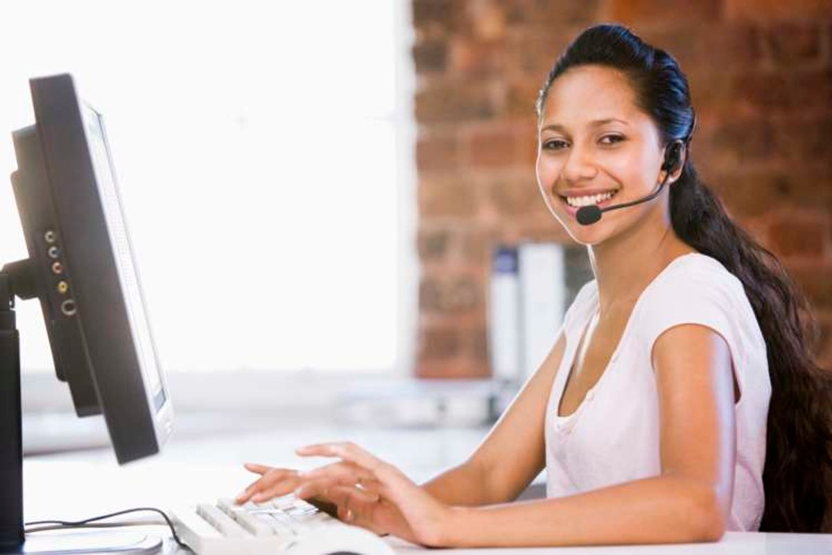 Businesswoman in office wearing headset and typing on computer s
