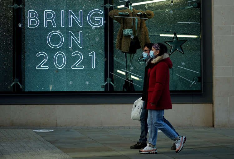 People walking past a shop sign in Manchester during the COVID-19 pandemic - Global Banking & Finance Review