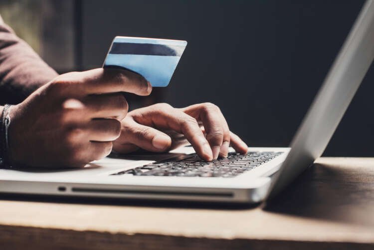 Man shopping online with a laptop, credit card in hand, reflecting retail finance trends - Global Banking & Finance Review