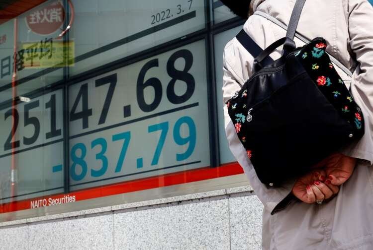 A woman wearing a protective mask, amid the coronavirus disease (COVID-19) outbreak, looks at an electronic board displaying Japan’s Nikkei index outside a brokerage in Tokyo