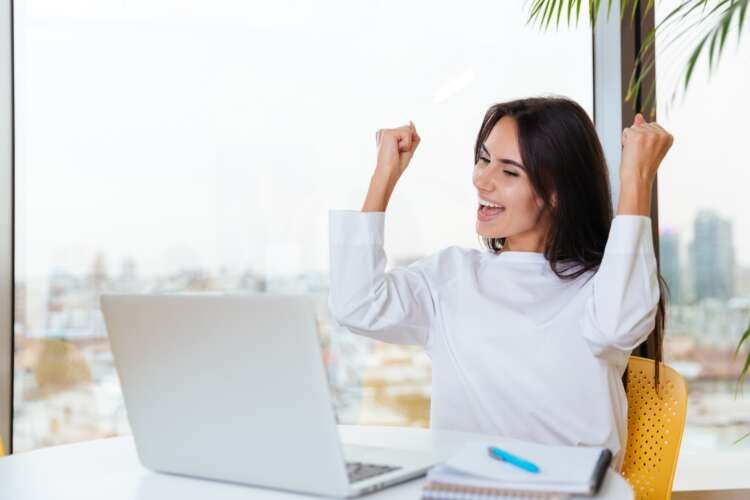 Cheerful young businesswoman celebrating success with a laptop related to personal loans - Global Banking & Finance Review