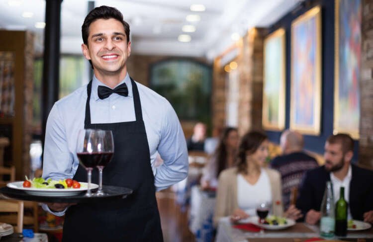 Professional waiter serving drinks in a busy restaurant - Hospitality Sector Challenges - Global Banking & Finance Review