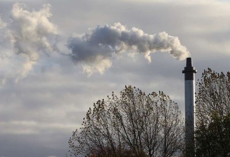 Smoke billowing from a chimney in Glasgow, symbolizing UK's manufacturing decline - Global Banking & Finance Review